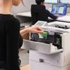 Woman replacing drum unit in Brother laser printer in modern office workspace