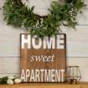 Wooden home sweet apartment sign with greenery wreath on white shiplap wall