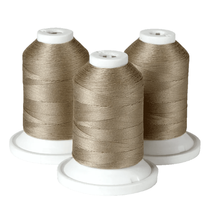 Three spools of taupe embroidery thread on white cones