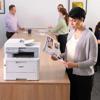 Woman using Brother all-in-one color laser printer in modern office environment