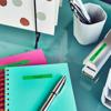 Brother label maker organizing notebooks and office supplies on teal desk