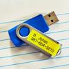 Brother TZe-641 laminated label tape on blue USB drive with personalized contact information