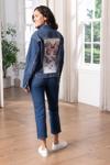 Woman wearing denim jacket with embroidered butterfly design in bright home interior