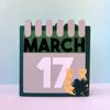 Decorative calendar showing March 17 with shamrock and pink tabs