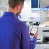 Man using smartphone to manage Brother color laser printer in office environment