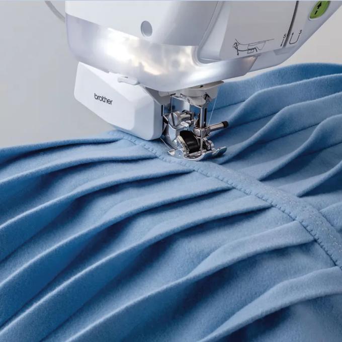 Brother sewing machine stitching blue fabric with presser foot detail