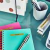 Brother label maker on desk with colorful notebooks and office supplies