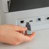 Hand inserting USB drive into Brother ADS-3350W wireless desktop scanner connectivity ports
