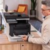 Man loading paper into Brother MFC-L8930CDW all-in-one color laser printer in home office