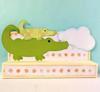 Green alligator-shaped wireless speaker with pink accents and cloud detail