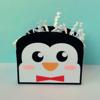 Penguin-shaped gift box with shredded paper filler and red bow tie accent