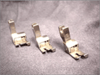 Three metal presser feet for Brother sewing machines on gray fabric background