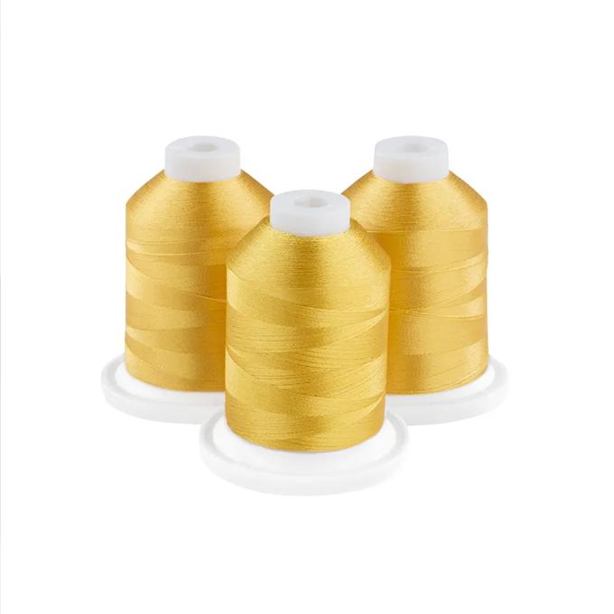 Three spools of golden yellow embroidery thread with white caps on white bases