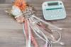 Brother label maker with keyboard on wooden table beside decorative floral wreath with ribbons