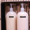 Dos botellas blancas con bomba etiquetadas champú y acondicionador con cinta Brother TZe-325