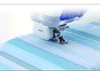 Brother sewing machine presser foot stitching decorative scalloped edge on blue striped fabric