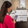 Woman using smartphone to print with Brother HL-L8430CDWT color laser printer in home office