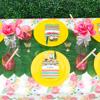 Colorful summer party table with tropical leaves, pink flowers, yellow plates, and striped place settings