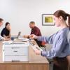 Woman reviewing color printout from Brother wireless laser printer in modern office meeting room