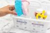 Hand organizing towels in labeled white bathroom storage baskets