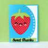Handmade card with smiling strawberry character on blue background with white polka dots