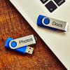 Etiqueta laminada Brother TZe-141 en unidad USB azul junto a laptop en escritorio