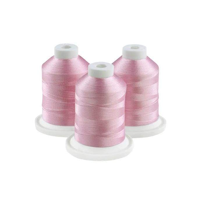 Three spools of pink embroidery thread on white bases