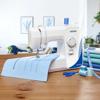 Brother FB1757X sewing machine with blue fabric and thread spools on wooden table