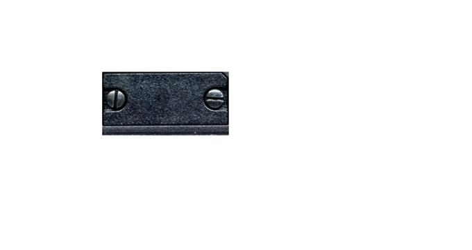 Close-up of black textured plastic component with two metal screws on flat surface
