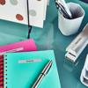 Brother label maker on desk with organized notebooks, pens, and labeled folders