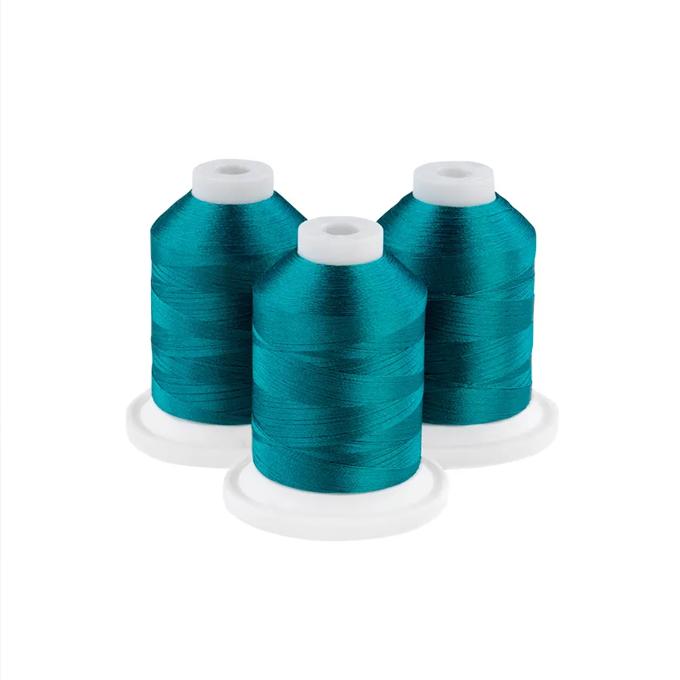Three spools of oceanic green embroidery thread on white bases