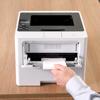 Brother HL-L6217DW monochrome laser printer with hand retrieving printed envelope from paper tray