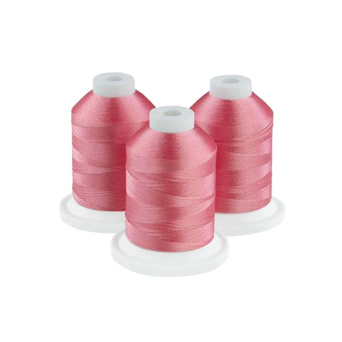 Three spools of rose-pink embroidery thread on white bases