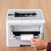 Brother HL-L5215DW monochrome laser printer with hand retrieving printed envelope from output tray