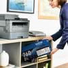 Woman holding Brother TN760 2-pack toner cartridge box near wireless laser printer in home office