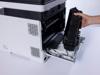 Hand removing toner cartridge from Brother laser printer with open front panel