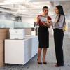 Two professionals reviewing documents beside Brother HL-L6415DW monochrome laser printer in office