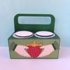 Green cardboard drink carrier with two pink cup holders and strawberry crown design