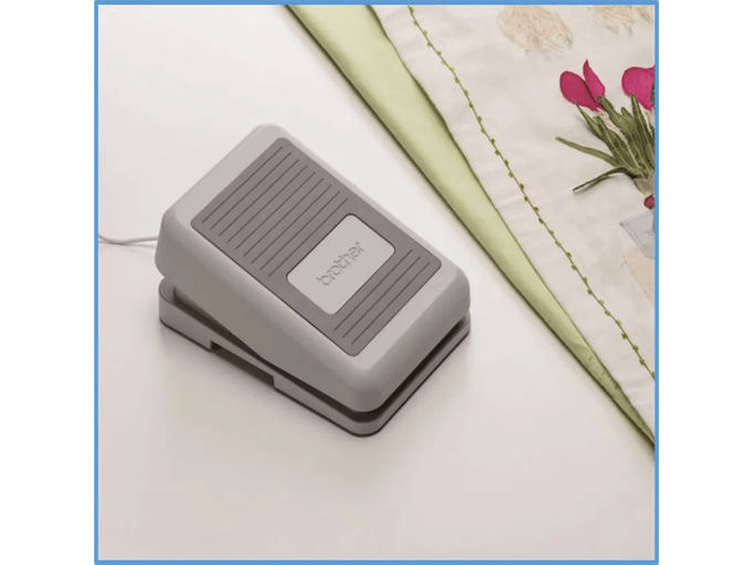 Brother foot pedal for sewing machine on white desk with fabric and flowers