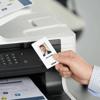 Hand holding ID card near Brother all-in-one color laser printer with wireless connectivity