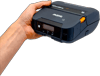 Hand holding Brother portable label maker with LCD display and orange accent