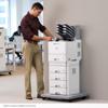 Man using Brother color laser printer with multiple paper trays in office