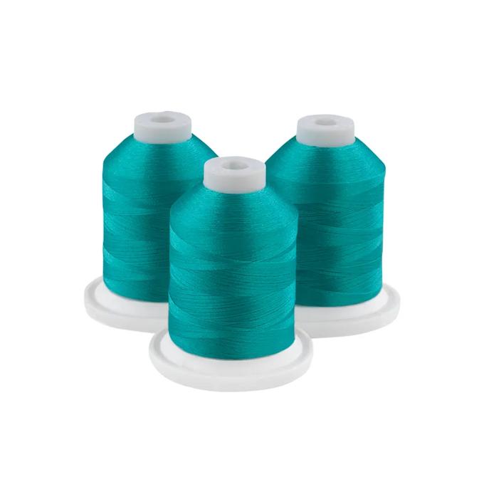 Three spools of Brother topaz embroidery thread on white bases