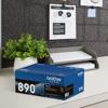 Brother TN890 high-yield toner cartridge on office desk with printer in background