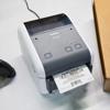 Brother TD-4D label printer printing barcode shipping label on white desk