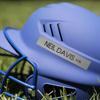 Blue football helmet with face guard and personalized name label on grass field