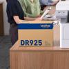 Brother DR925 drum unit on desk beside laser printer in office setting