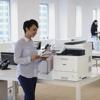 Woman using Brother color laser all-in-one printer with touchscreen in modern office