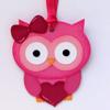 Pink owl craft ornament with bow and heart on white background