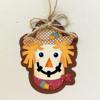 Handmade scarecrow ornament with polka dot hat and twine bow on textured background